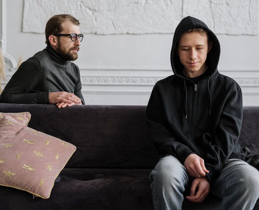 LGBTQ+ Mental Health: Teen in hoodie with therapist, addressing mental health concerns in a supportive environment.