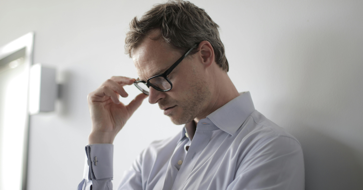 Man with glasses, looking stressed, representing challenges of managing immature personality disorder.