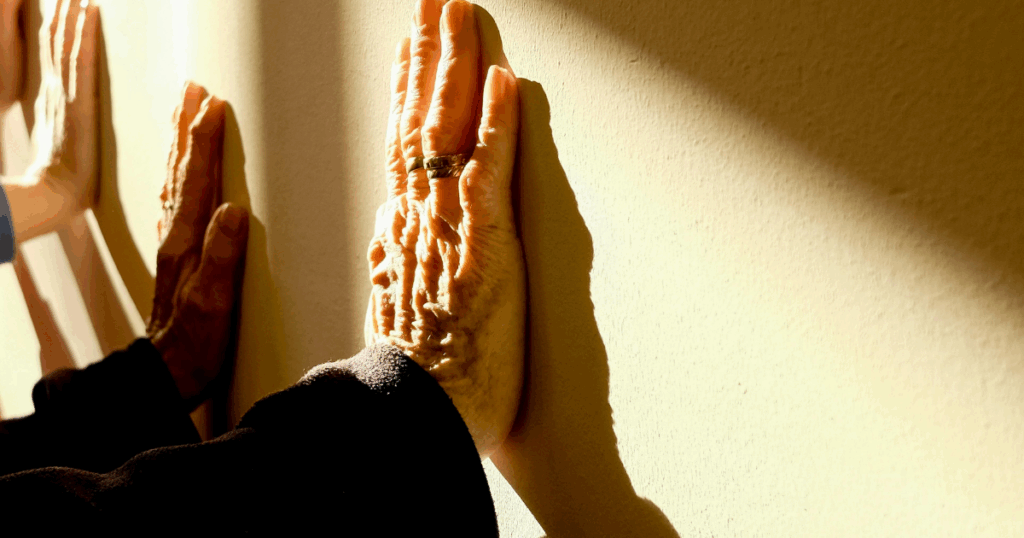 Genetic factors in bipolar disorder concept: Close-up of hands pressed against a wall, representing stress and mental health.