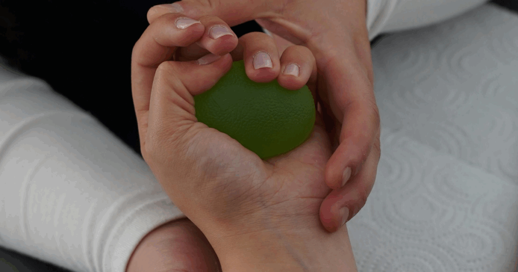 Hand squeezing a green stress ball for mental health rehabilitation, promoting relaxation and healing pathways.
