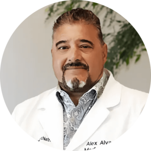 Dr-Alejandro-Alva-1-1webp - Los Angeles Mental Health - Los Angeles Mental Health Portrait of Dr. Alex Alva in a white lab coat, smiling, indoors with greenery in the background.