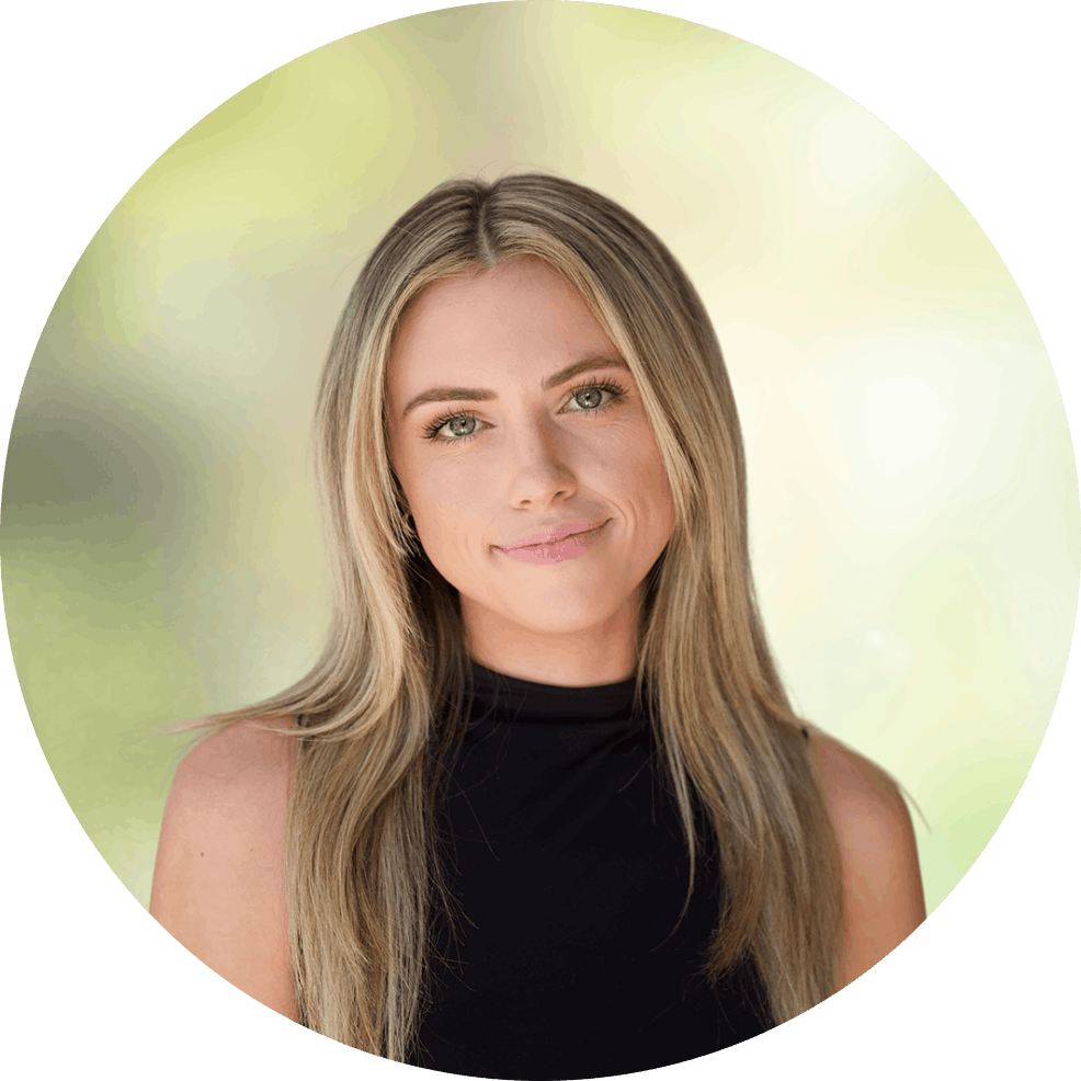 Portrait of a smiling woman with long blonde hair, wearing a black sleeveless top, outdoors with a soft green background