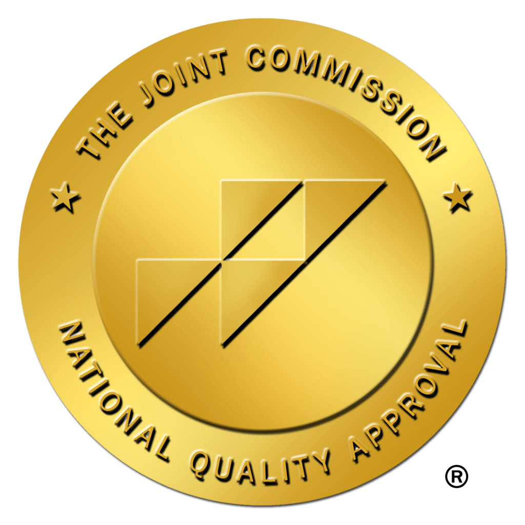 Gold medal seal indicating Joint Commission National Quality Approval, with a geometric center design and star accents in the border.